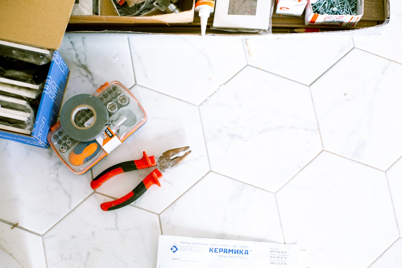 ours-journey A selection of home renovation tools placed on a white tiled floor, ready for use.