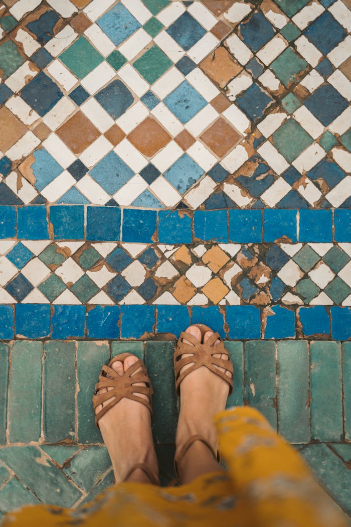 about-02 Top-down view of sandals on intricate Moroccan mosaic tiles, showcasing traditional patterns.