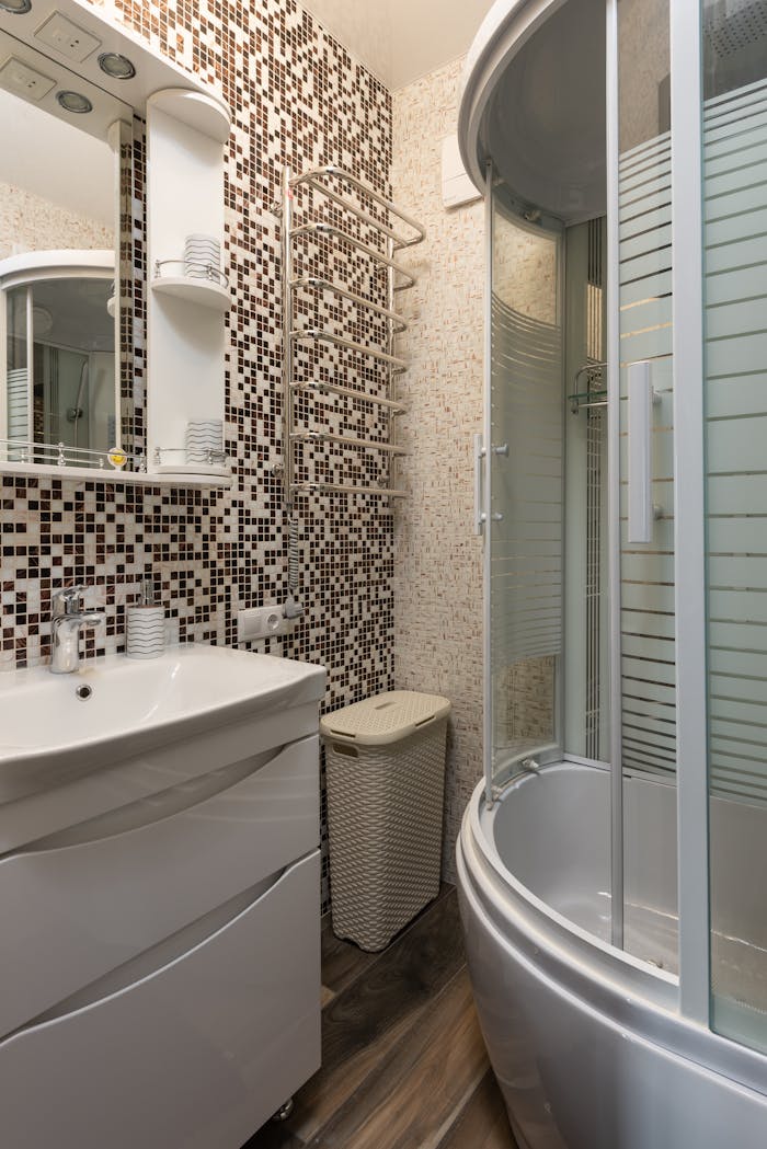 about-img Stylish bathroom featuring mosaic tiles, round shower, and modern fixtures.
